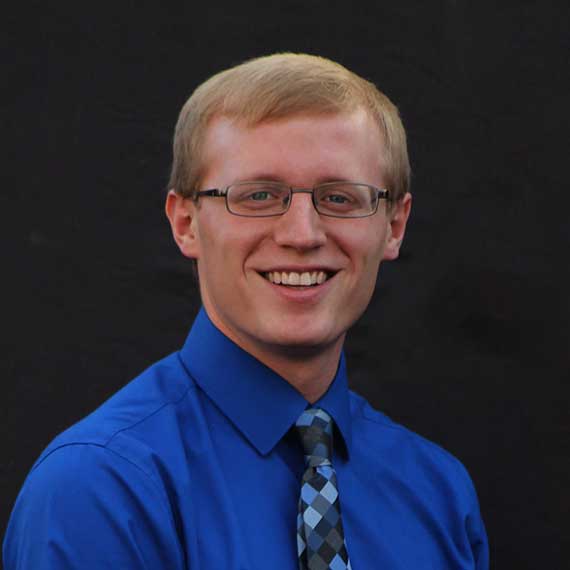 Trey Sims in blue shirt with dark background