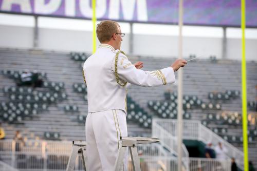 Trey in uniform conducting on podium.